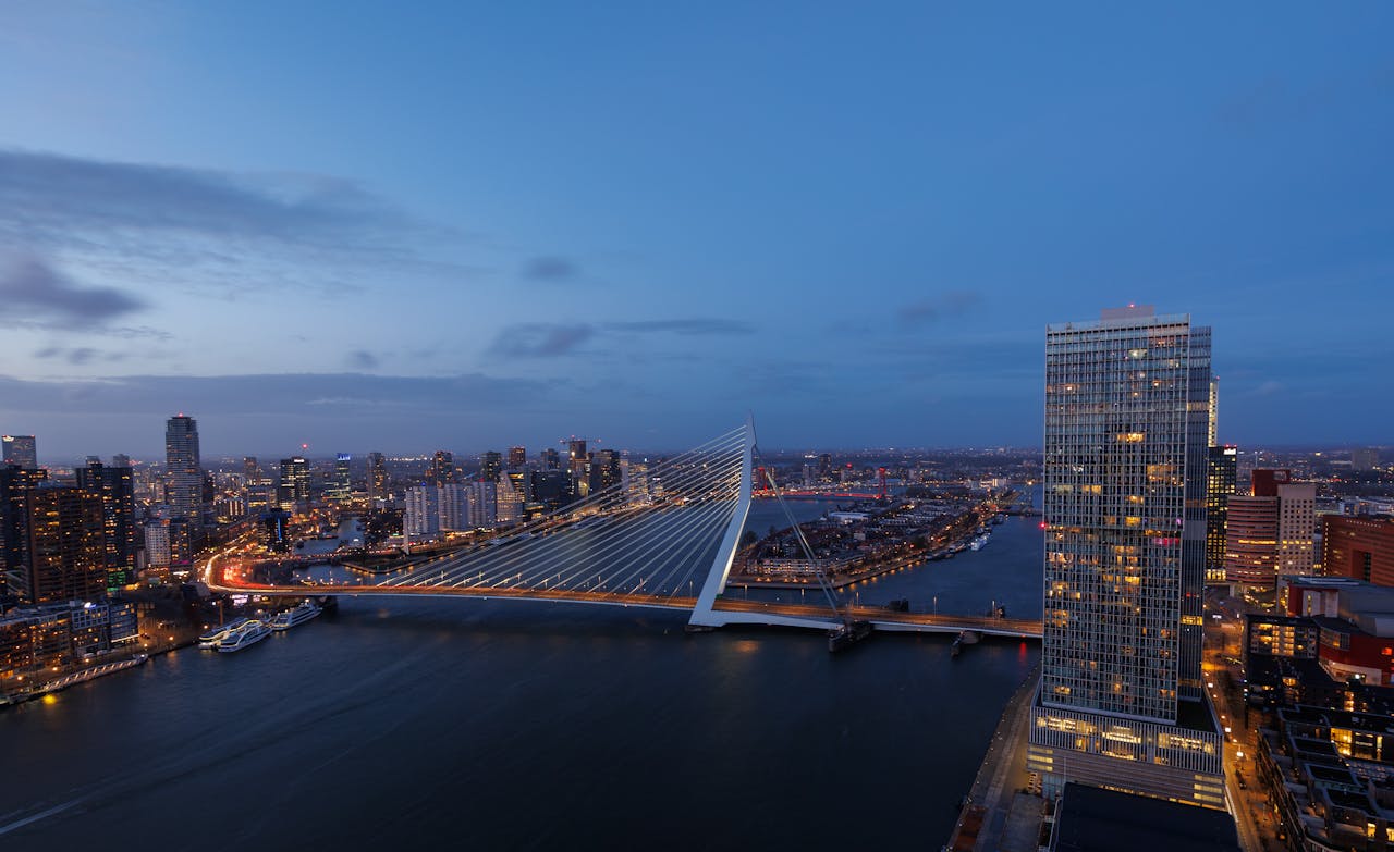 Crafting Captivating Headlines: Your awesome post title goes here Stunning aerial view of the illuminated Erasmus Bridge and Rotterdam skyline at dusk.